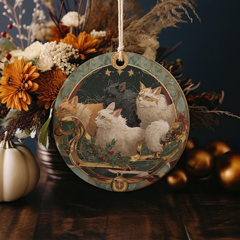 A circular ornament featuring a group of cats, including a black cat, a white cat, and two orange cats, surrounded by autumn flowers and a sailboat.