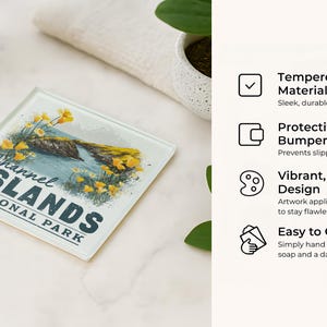 a glass coaster with a design of the Channel Islands National Park, placed on a marble surface next to a glass of water and a plant.