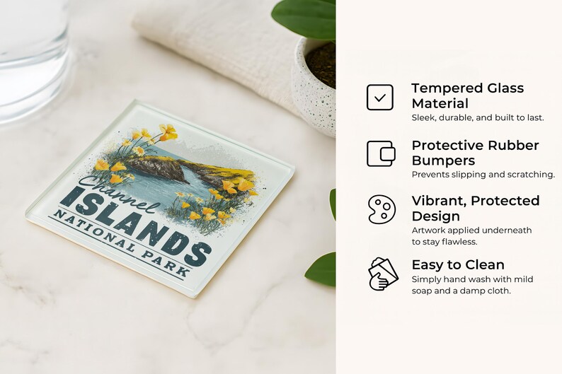 a glass coaster with a design of the Channel Islands National Park, placed on a marble surface next to a glass of water and a plant.