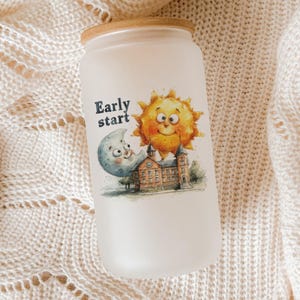 May include: Frosted glass tumbler with a bamboo lid. The tumbler features a whimsical illustration of a smiling sun, moon, and building with the text "Early start". The design is in watercolor style.