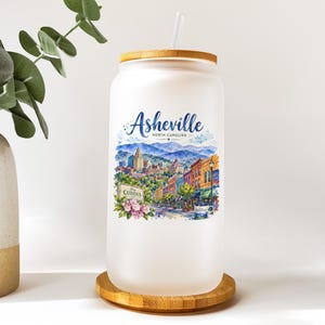 A white ceramic mug with a label that says "Ashville, North Carolina" and features an illustration of a cityscape.