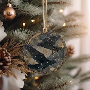 a Christmas tree decorated with ornaments, including a circular ornament with a bird design and a gold and black ornament.
