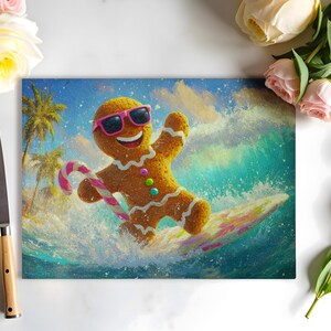 May include: A rectangular cutting board featuring a gingerbread man surfing a wave. The gingerbread man wears pink sunglasses and holds a candy cane. Palm trees and a blue sky form the background. The board has a colorful, artistic design.