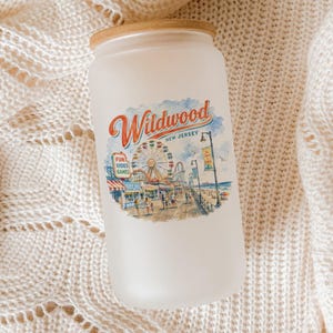 A frosted glass jar with a printed design of a carnival scene, placed on a white knitted blanket.