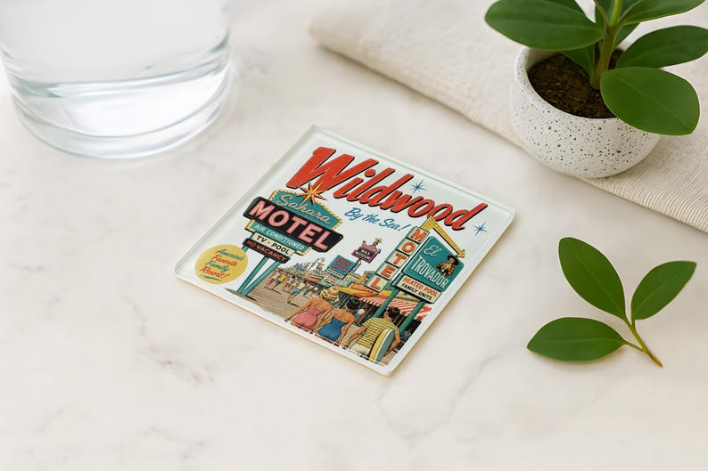 a coaster with a vintage-style illustration of the Wildwood Motel, surrounded by various objects such as a glass of water, a potted plant, and a leaf.