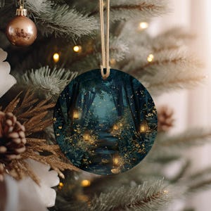 May include: Round Christmas ornament featuring a forest scene with a path illuminated by lanterns. The artwork depicts a dark, enchanting forest with a pathway leading into the distance. The ornament is hanging on a Christmas tree with other ornaments.