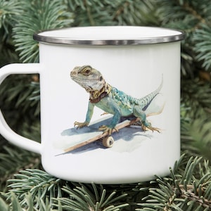 May include: White enamel mug featuring a watercolor illustration of a turquoise and blue lizard on a skateboard. The lizard has a brown and yellow collar. The mug has a silver rim and a white handle.