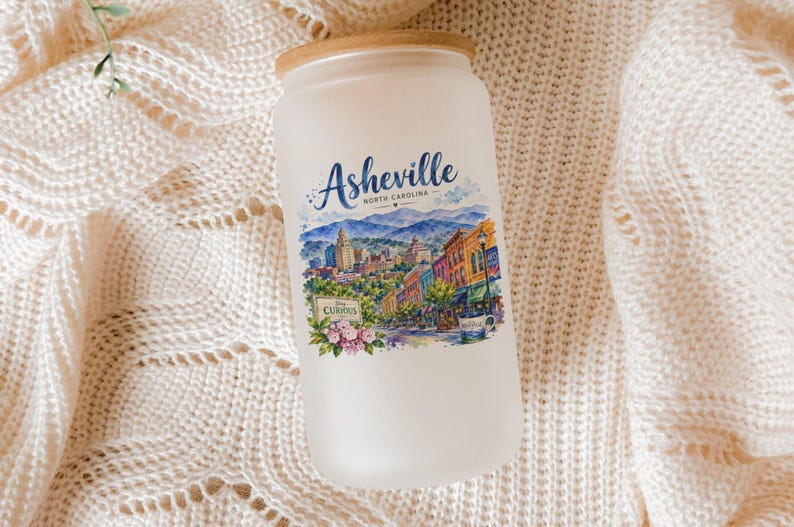 A frosted glass jar with a label depicting a scenic cityscape of Asheville, North Carolina.