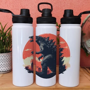 May include: Three white stainless steel water bottles with black lids and a graphic of Godzilla in front of a red sun. The bottles are on a wooden surface.