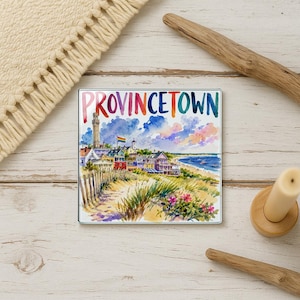 May include: A square magnet featuring a watercolor painting of Provincetown, with the town's name in rainbow colors. The image depicts a beach scene with colorful buildings, a lighthouse, and a rainbow flag.
