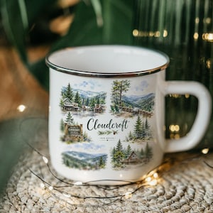 May include: White enamel mug with a silver rim, featuring watercolor illustrations of Cloudcroft, New Mexico. The design includes images of cabins, trees, and mountains, with the town's name prominently displayed.