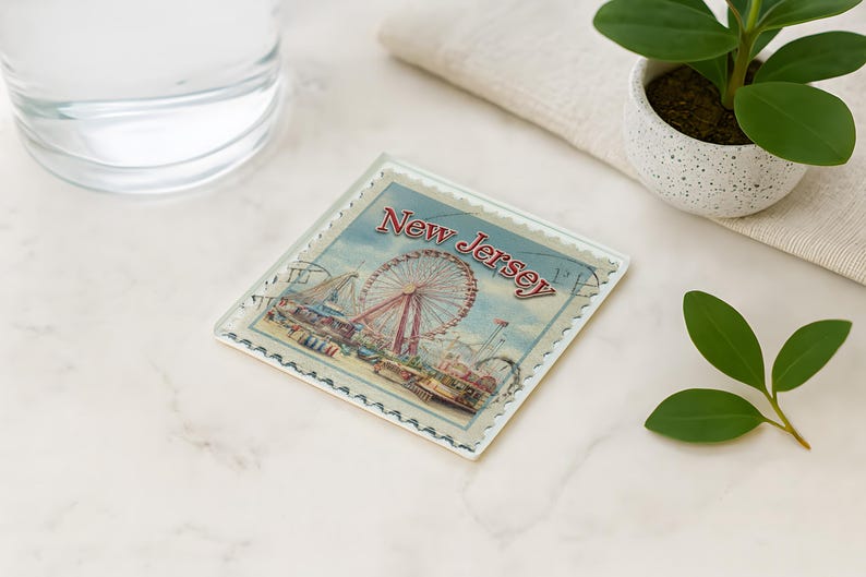 a coaster with a ferris wheel and a water glass on a marble surface, along with a potted plant and a leaf.