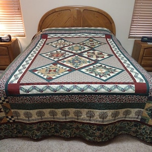 Può includere: Una trapunta verde, marrone e crema con un design a patchwork che presenta una varietà di forme geometriche. La trapunta è realizzata con una varietà di tessuti e ha un aspetto rustico e campestre.