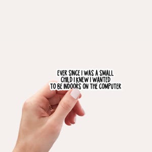 May include: A white sticker with black text that reads: "EVER SINCE I WAS A SMALL CHILD I KNEW I WANTED TO BE INDOORS ON THE COMPUTER." The sticker is held by a hand.