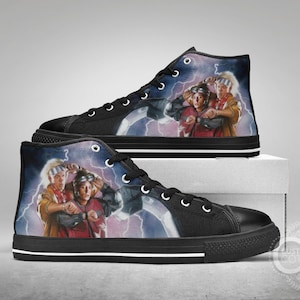 May include: A pair of black high-top canvas shoes with a white stripe around the sole. The shoes feature a colorful image of two characters from the movie Back to the Future, surrounded by lightning bolts.