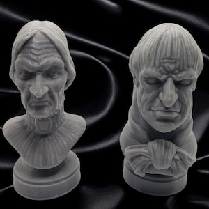 May include: Two gray 3D printed busts of people with detailed facial features. The bust on the left has a high collar and the bust on the right has a bow tie.
