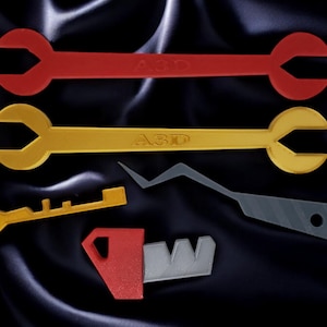 May include: A set of four tools, including two wrenches, a key, and a pry bar. The wrenches are red and yellow, and the key and pry bar are yellow and gray. The wrenches are labeled "A3D".