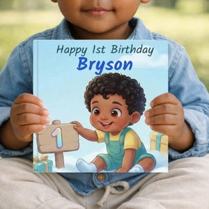 May include: A children's book with the text "Happy 1st Birthday Bryson" on the cover. The illustration features a cartoon baby with curly hair, wearing overalls, and holding a sign with the number 1. The book is held by a person.