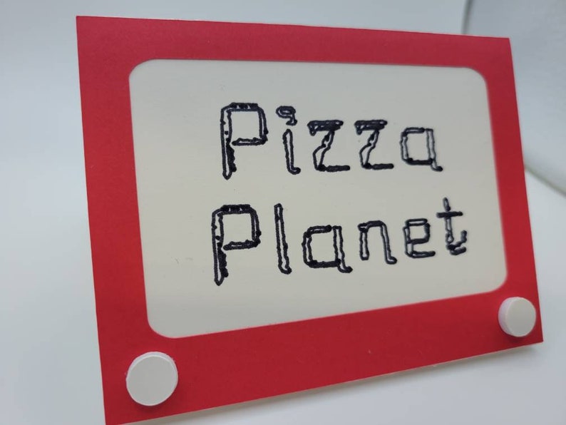 May include: Red and white sign with a white frame and a black inscription that reads "Pizza Planet".