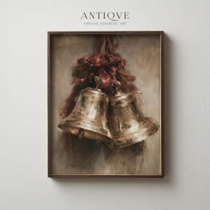 Puede incluir: Una impresión de pintura al óleo enmarcada que muestra dos campanas de metal dorado atadas con una cinta de color rojo oscuro. La obra presenta una textura suave y pictórica con tonos marrones y crema, dentro de un marco de madera.