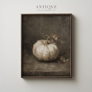 Puede incluir: Una impresión artística estética vintage enmarcada que presenta una naturaleza muerta de una calabaza blanca. La calabaza tiene una superficie texturizada y se encuentra sobre un fondo oscuro y apagado. La impresión está enmarcada en un marco de madera marrón oscuro. El texto "ANTIQVE VINTAGE AESTHETIC ART" está en la parte superior.