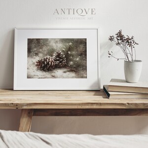 May include: Two brown pine cones on a snowy forest floor with a blurred background of green trees and white snow. The pine cones are in focus and the background is out of focus.