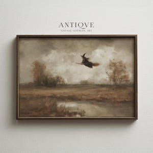 May include: A framed vintage painting depicts a witch flying on a broomstick over a landscape. The artwork features a muted color palette of browns, grays, and tans, with the text "ANTIQVE VINTAGE AESTHETIC ART" at the top.