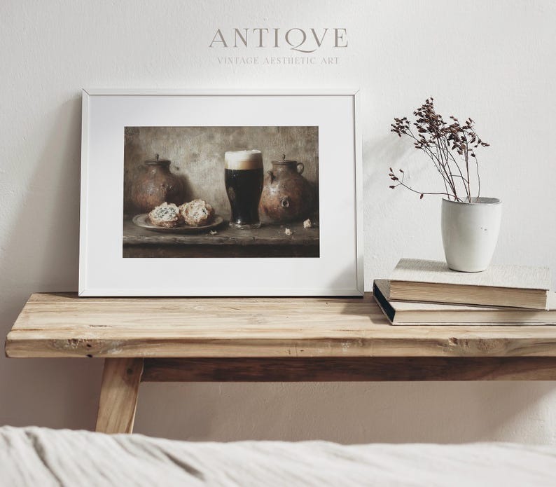 May include: A framed print of a still life featuring a glass of dark beer, two ceramic jugs, and two pastries on a wooden table. The print has a vintage aesthetic and is titled "Antique Vintage Aesthetic Art".