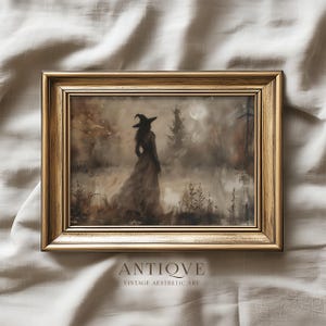 May include: A framed vintage aesthetic art print featuring a witch in a long dress and hat, standing in a misty forest under a full moon. The artwork is in muted tones of brown, beige, and gray, with the word "ANTIQVE" at the bottom.
