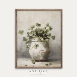 May include: A vintage-style painting depicting a white ceramic vase filled with green leaves. The vase has a rustic, textured surface and is set against a light grey background. The painting features a soft, muted colour palette and a simple, elegant design.