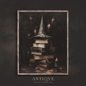 Puede incluir: Una pintura enmarcada que representa una pila de libros antiguos con un sombrero de bruja en la parte superior. Los libros son de varios tonos de marrón y tienen un aspecto desgastado y antiguo. El sombrero es de color gris oscuro y tiene un ala ancha. El fondo es de un color oscuro y sombrío, con pequeñas luces blancas dispersas por la imagen. El texto "ANTIQVE" y "VINTAGE AESTHETIC ART" está en la parte inferior de la imagen.