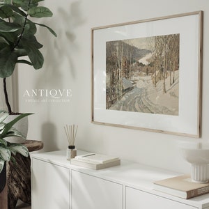 May include: A framed vintage art print of a snowy winter scene with a road leading through a forest. The print is in a light wood frame and is hanging on a white wall. The text "ANTIQVE VINTAGE ART COLLECTION" is visible below the print.