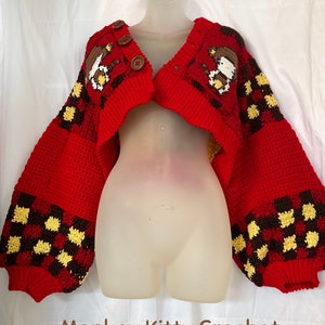 May include: A red crocheted cardigan with a checkered pattern and brown cartoon characters. The cardigan has a V-neck and button closure. The text "Monkey Kitty Crochet Patterns" is visible at the bottom of the image.
