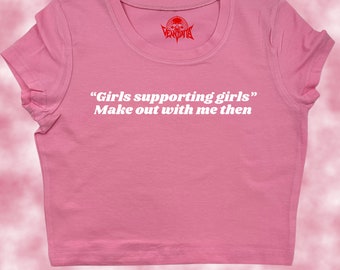 Puede incluir: Camiseta rosa de manga corta y corte crop con el texto "Girls supporting girls" Make out with me then" en blanco.