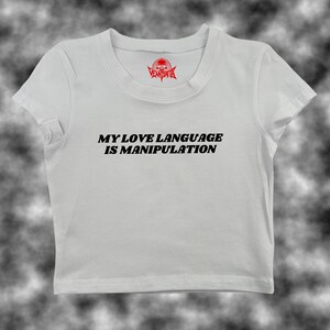 May include: White cropped t-shirt with black text that reads "My love language is manipulation".