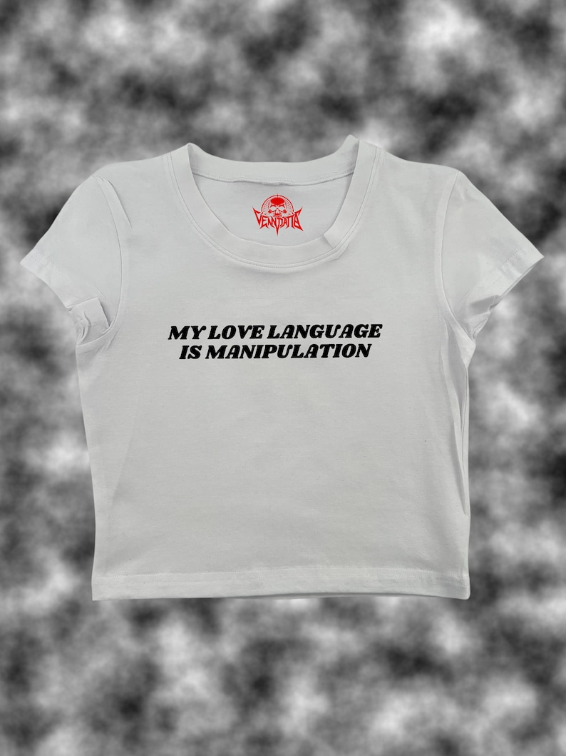 May include: White cropped t-shirt with black text that reads "My love language is manipulation".