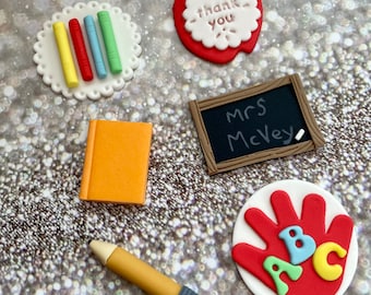 Puede incluir: Un conjunto de seis adornos para pasteles de agradecimiento a los profesores. Los adornos incluyen una manzana roja con las palabras "gracias", una pila de libros coloridos, una pizarra marrón con las palabras "Sra. McVey", un lápiz amarillo, un libro naranja y una huella de mano roja con las letras "ABC" en diferentes colores.