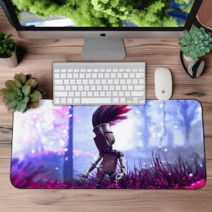May include: A rectangular mouse pad featuring a stylized illustration of a figure with a feathered headdress and armor, set against a backdrop of purple and blue hues. The design is surrounded by tall, magenta-colored grass.