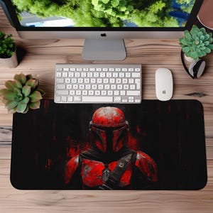 Op de afbeelding: Een zwarte en rode gaming muismat met een gestileerde afbeelding van een Mandalorian-krijger in een rode en zwarte helm en harnas.