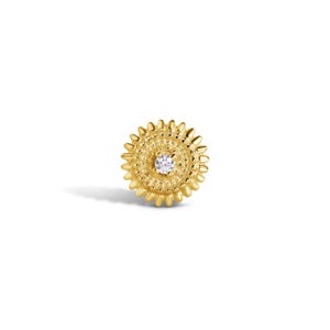 May include: A circular gold stud earring featuring a textured, sunburst-inspired border with radiating rays. The center of the earring has a granulated surface and is set with a single, small, clear, round-cut gemstone at the very middle point.