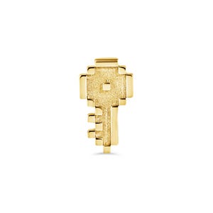 May include: A gold-toned pendant shaped like a stylized key with a rectangular head and a textured, granular surface. The design features a central square cutout on the head and a stepped, block-like bit extending from the bottom of the shaft.