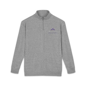May include: A heather gray long-sleeve pullover with a quarter-zip collar. The shirt features a small purple logo on the upper left chest. The logo includes a house icon and text below it. The background is plain white.