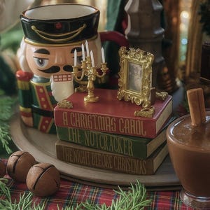 Könnte beinhalten: Eine weihnachtliche Dekoration mit einem Nussknacker-Behälter, einem Stapel Bücher mit Weihnachtsthemen, einem kleinen goldfarbenen Bilderrahmen und einem goldenen Kerzenhalter mit brennenden Kerzen. Das Arrangement steht auf einem karierten Stoff.