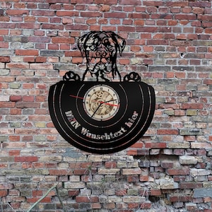 Könnte beinhalten: Schwarze Schallplattenuhr mit einer Silhouette eines Rottweilers, der die Schallplatte hält. Das Zifferblatt der Uhr ist ein kleinerer Kreis mit einem Zahnrad-Design. Der Text "Dein Wunschtext hier" ist auf die Schallplatte gedruckt.