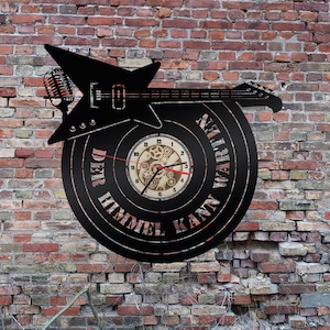 May include: Black vinyl record clock with a silhouette of an electric guitar and the text "Der Himmel Kann Warten".