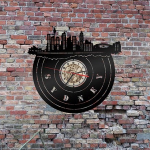 Op de afbeelding: Zwarte vinyl platen klok met een silhouet van de skyline van Sydney en het woord "SYDNEY" rond de wijzerplaat.