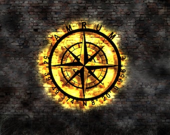 May include: A black compass with a gold background on a brick wall. The compass has the letters "AMRUM" around the edge and numbers indicating degrees. The compass is illuminated with a warm yellow glow.