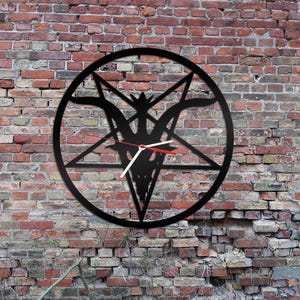 May include: Black metal wall clock featuring a pentagram design with a goat's head at its centre. The clock hands are red and white.