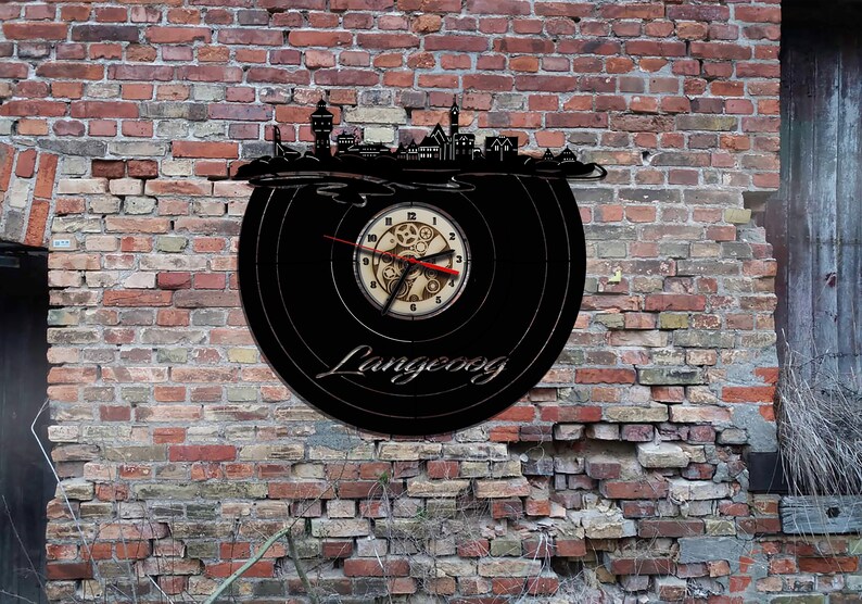 May include: Black vinyl record clock featuring a cityscape silhouette and the word "Langeoog" on the face. The clock hands are red and the clock face is white with black numbers.