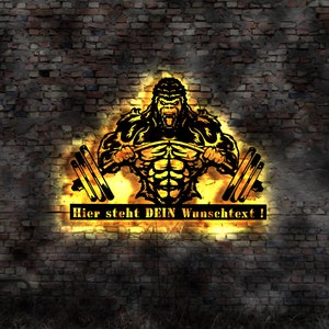 Puede incluir: Una ilustración en blanco y negro de un gorila musculoso levantando pesas contra un fondo de pared de ladrillo. El gorila está iluminado con una luz amarilla brillante. El texto "Hier steht DEIN Wunschtext!" está debajo del gorila.